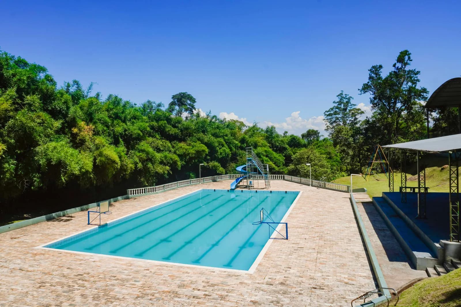 Piscina ao ar livre com toboágua, cercada pela mata